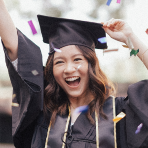 A happy young woman in graduation attire joyously celebrating with confetti in the air.