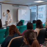 A male presenter delivering a lecture on children's rights in front of a classroom full of attentive adult learners.